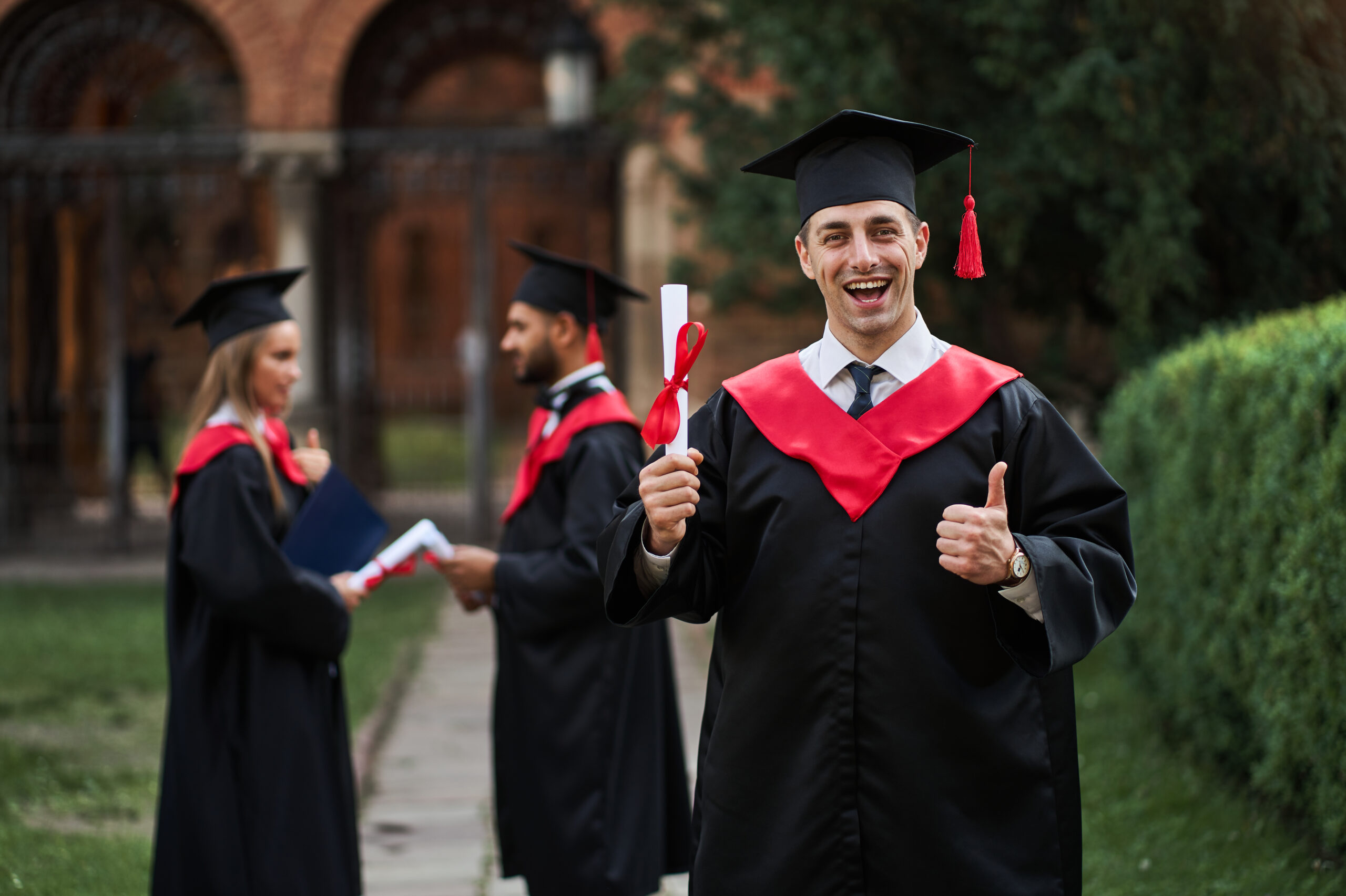 Happy caucasian graduate with his classmates in graduation gown